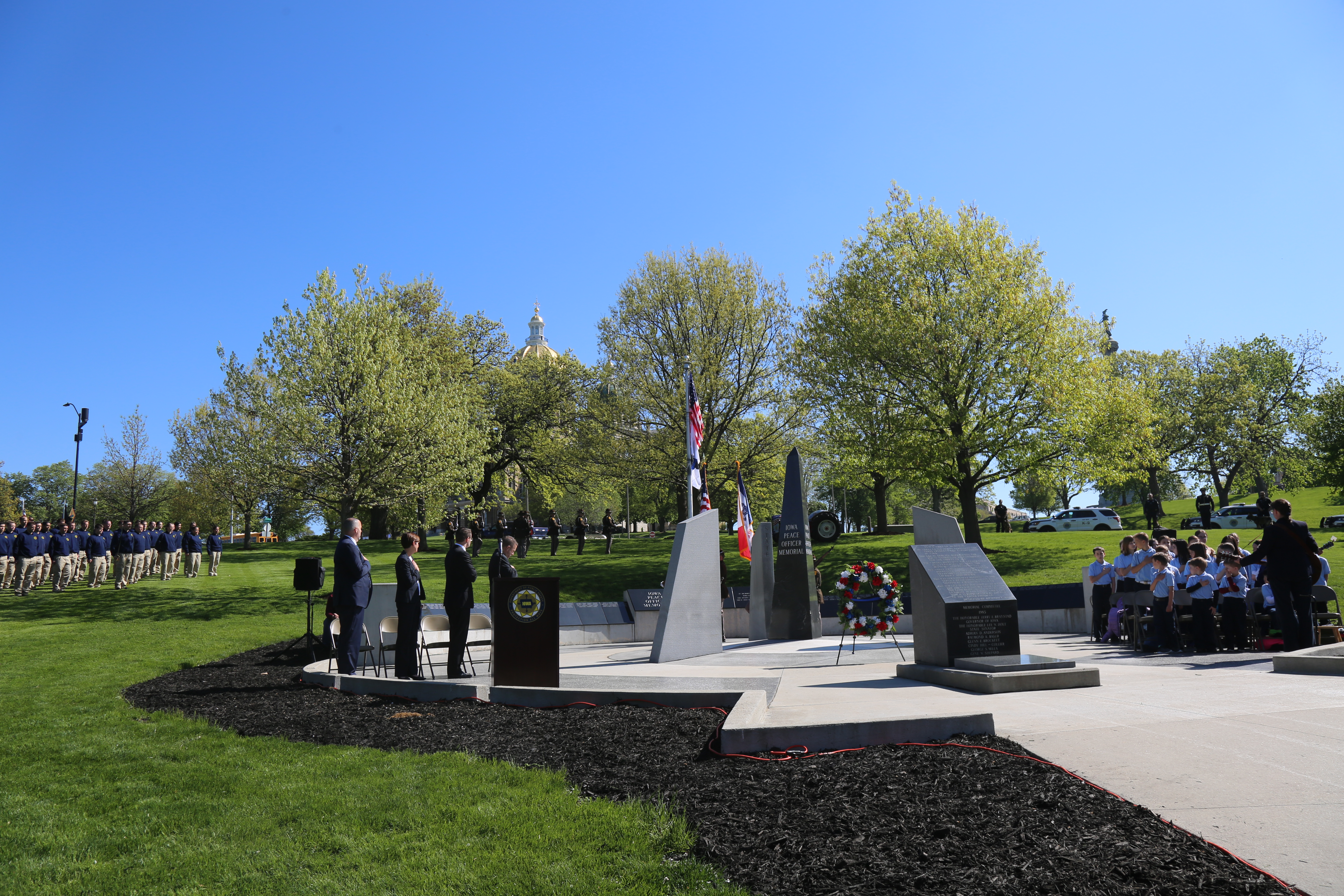 Photo of ceremony featuring monument, Governor Kim Reynolds, Lt. Governor Gregg, DPS Commissioner Bayens and guests